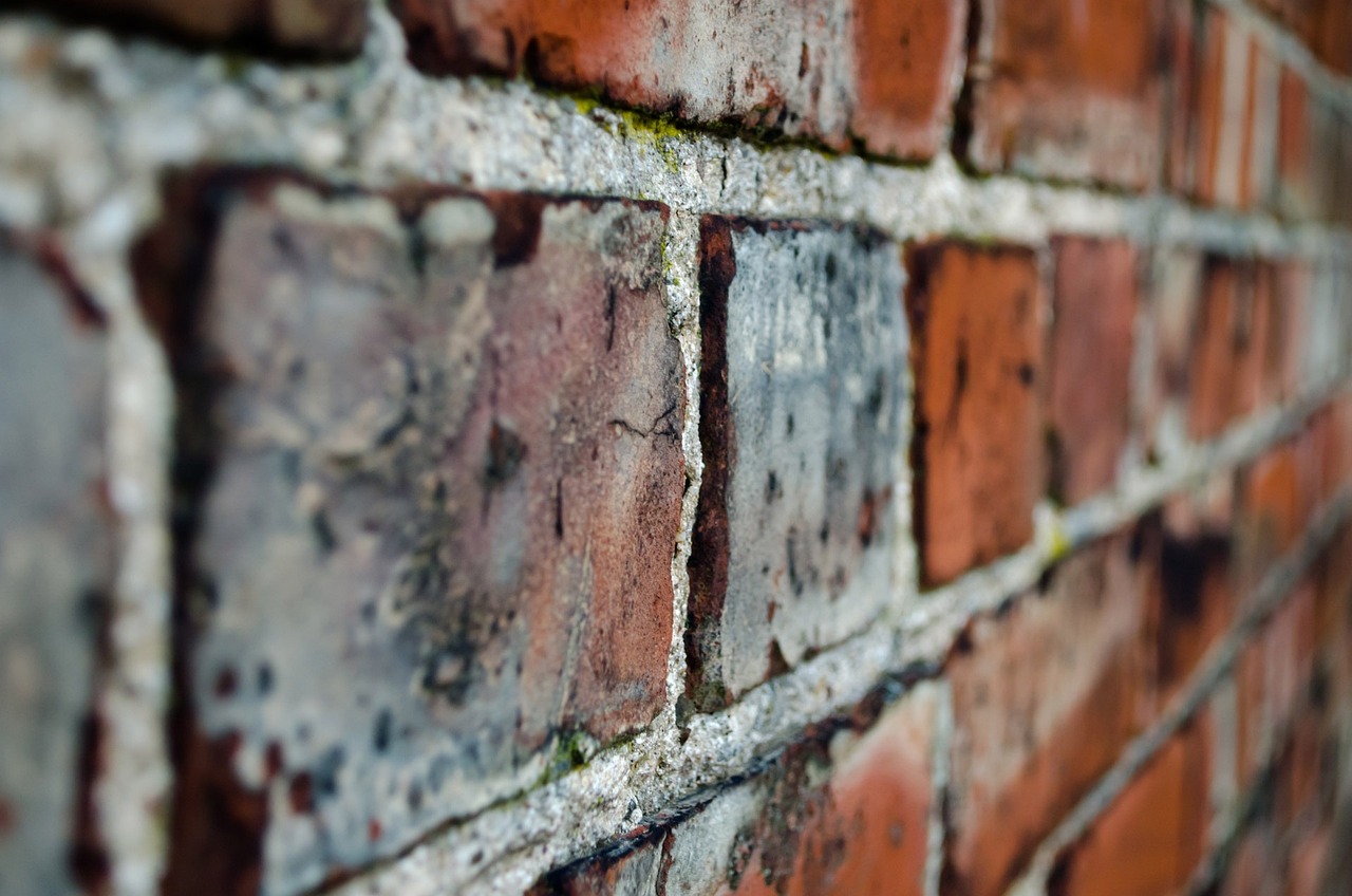 Hand repointing fresh mortar into a brick wall